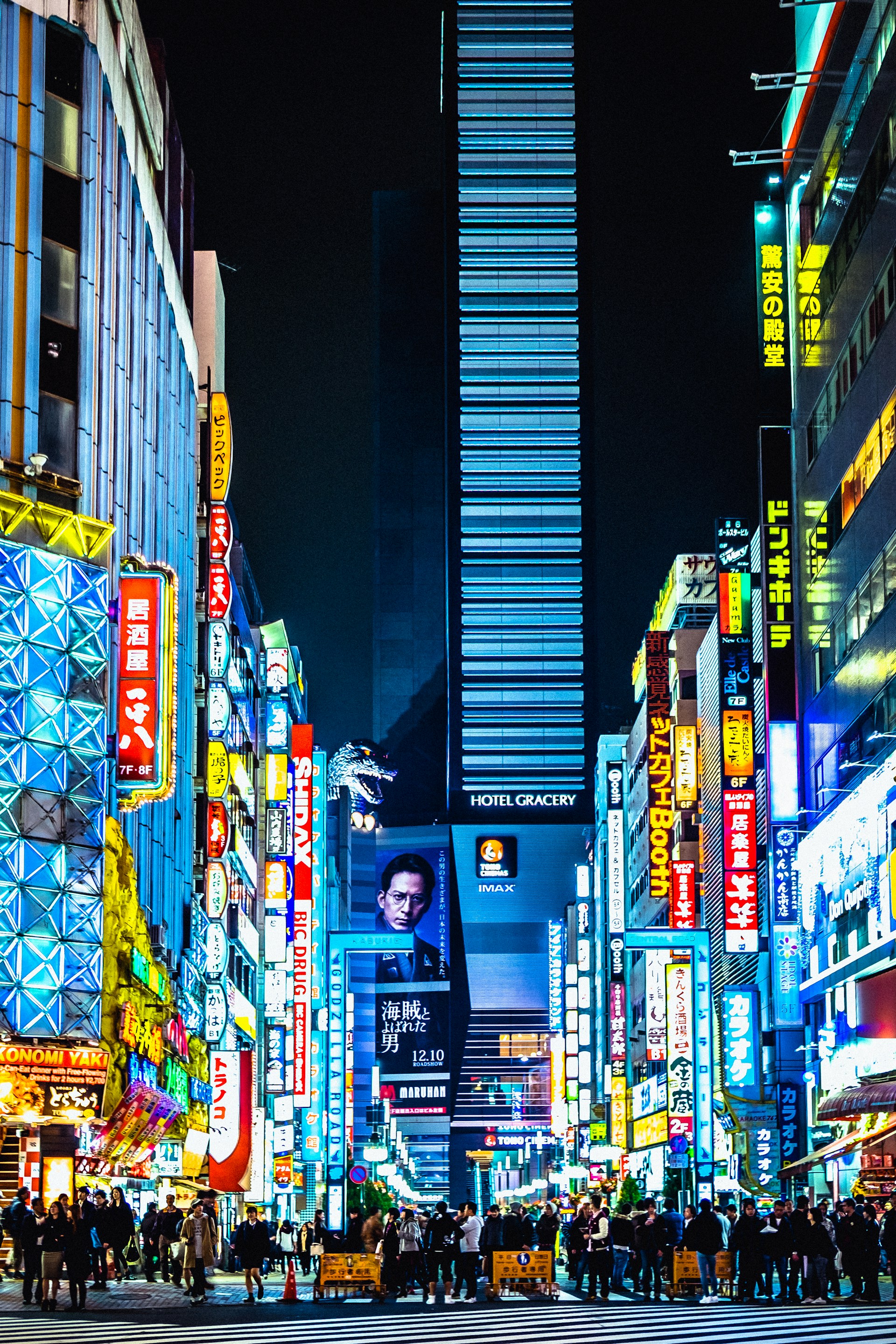 Neon signs towering over a Shinjuku street at night